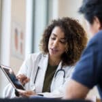 Female doctor uses tablet to show device to senior man